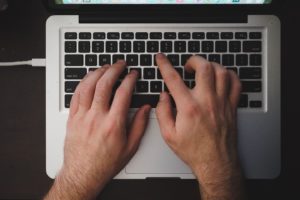 hands typing on Macbook keyboard