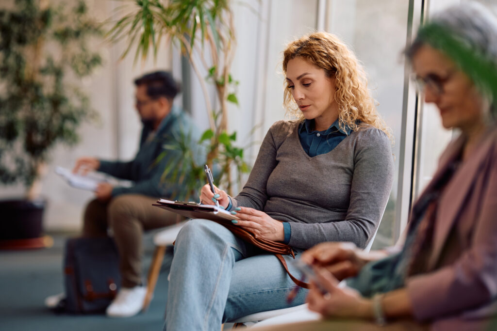 Adult woman filling out paperwork while waiting for an appointment at doctor's office.